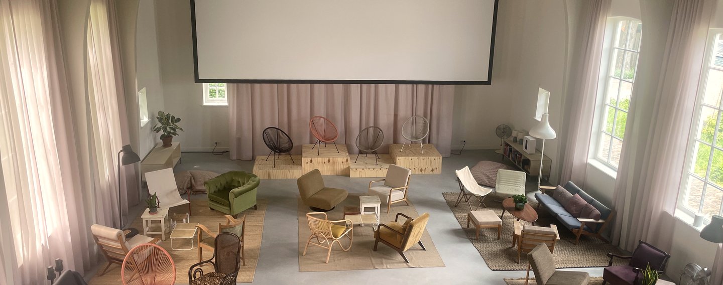 Helium House on Texel set up for an event: chairs arranged with projector screen and pink curtains